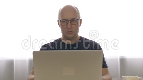 戴眼镜的人的概念商人用笔记本电脑在明亮的房间工作视频的预览图