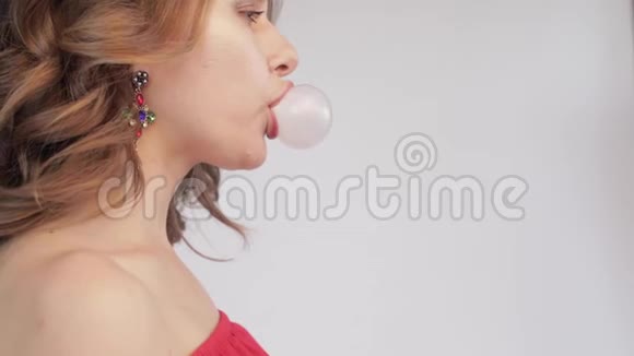 年轻女子吹粉色泡泡糖的侧景视频的预览图