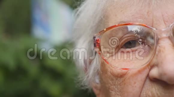 多莉在户外戴眼镜的老妇人一位有皱纹的老太太的眼睛特写肖像画视频的预览图