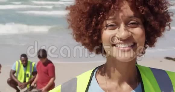 非洲裔美国女性志愿者在海滩上观看摄像机的正面景色视频的预览图