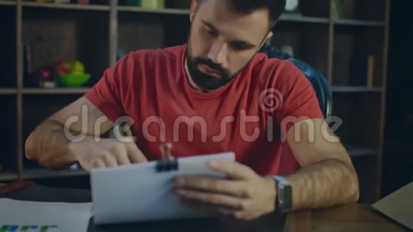 一位年轻的商人晚上在办公室用钢笔写商务文件视频的预览图