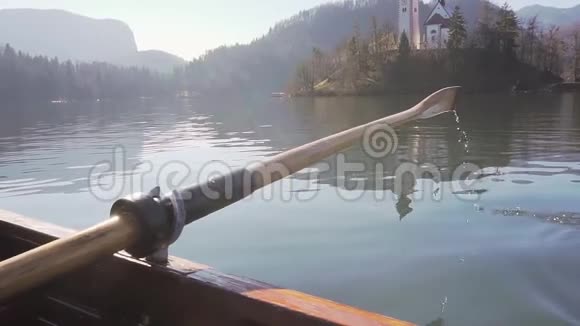 在阳光明媚的日子里一只桨在水中划桨在背景的湖中划桨斯洛文尼亚视频的预览图