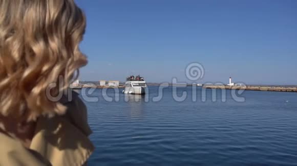 穿着老式西装的壕沟里迷人的年轻金发女人正坐在游艇码头上视频的预览图