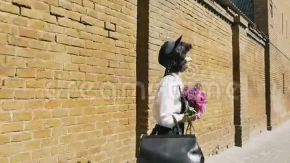 一个戴着帽子的漂亮女孩沿着石楼散步视频的预览图