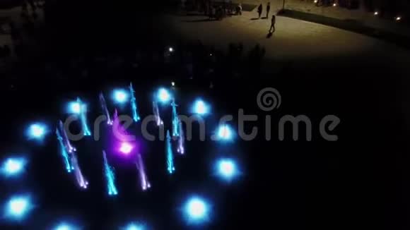 空中4k镜头舞蹈彩色喷泉在夜间彩色水射流在黑暗中用灯照明视频的预览图