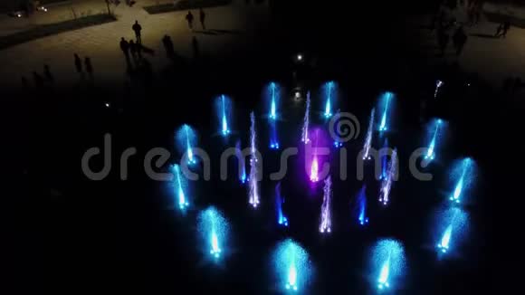 空中4k镜头舞蹈彩色喷泉在夜间彩色水射流在黑暗中用灯照明视频的预览图