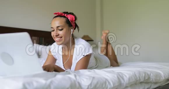 年轻女子用笔记本电脑进行视频聊天称美女为躺在床上的早晨视频的预览图