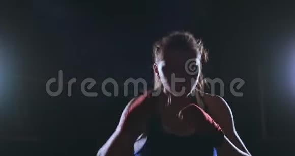 美丽性感的女拳击手直接对着镜头在黑暗的背景下向前移动视频的预览图