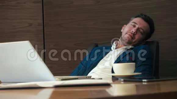 睡在椅子上的商人从办公室的电话和揉眼睛中醒来视频的预览图