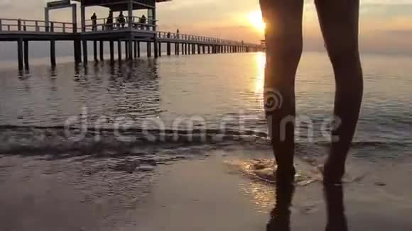 录像片段日出时沙滩沙滩海浪上的女人腿视频的预览图