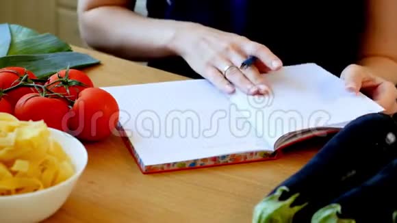 女人在笔记本上写收据桌子上的蔬菜视频的预览图