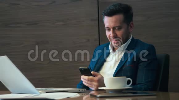 成功的商人坐在桌边手里拿着手机视频的预览图