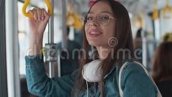 年轻时尚的女性在现代有轨电车中享受旅行站在公共交通工具中喝咖啡视频的预览图