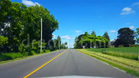 在明亮的夏日驾驶农村沿着美丽的阳光路的司机视角视频的预览图