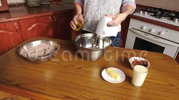 女人在搅拌好的鸡蛋里加油然后在碗里和电动搅拌器混合视频的预览图