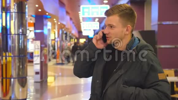 年轻的帅哥在购物中心用手机说话快乐微笑的男人在智能手机室内讲话关门视频的预览图