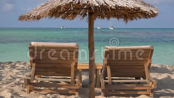 在热带异国海滩上有两个空木躺椅日光浴床和大苇伞视频的预览图