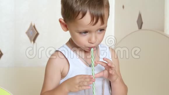 小孩用吸管喝杯子里的果汁做鸡尾酒视频的预览图