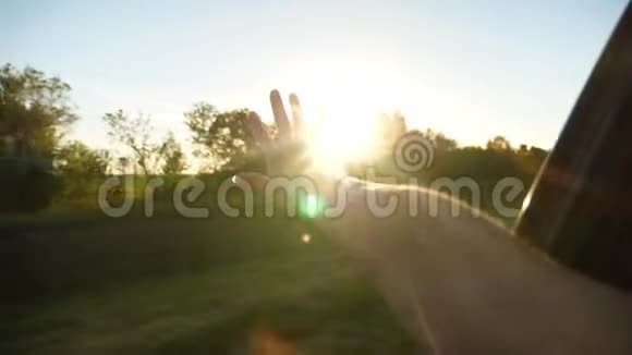 女人从车窗上挥动她的手捕捉阳光慢动作视频的预览图