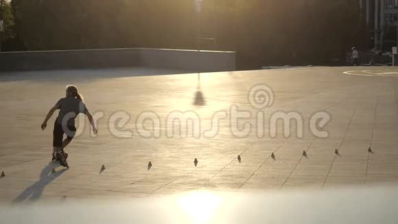 傍晚时分年轻的长发男子溜冰者正在一个城市公园里的球果间跳舞自由式回转视频的预览图