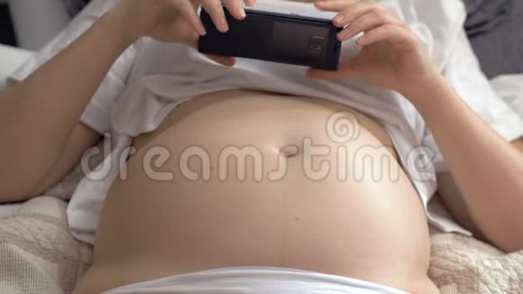 赤腹孕妇在家休息使用手机视频的预览图