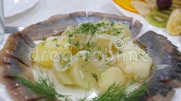 将鲱鱼切在盘子上用煮好的土豆撒上洋葱餐馆里的服务台美味可口的食物视频的预览图