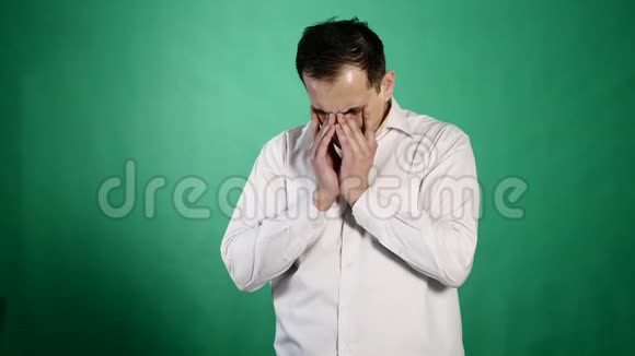 一个哭泣的人的特写肖像一个年轻的商人在绿色的背景上泪流满面闭上了疼痛的眼睛视频的预览图