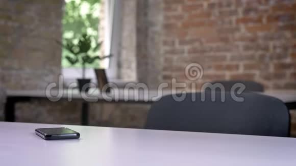 手机躺在空荡荡的现代化办公室的桌子上视频的预览图