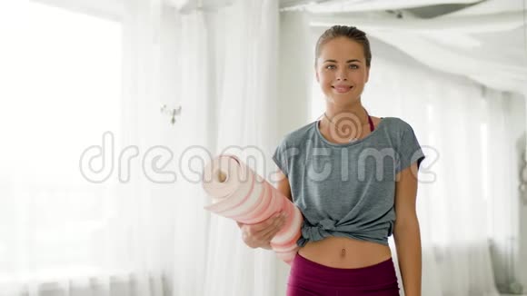 在瑜伽馆拿垫子的女人竖起大拇指视频的预览图