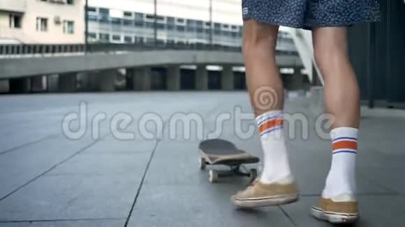 男腿在滑板上玩花样滑板脚在城市滑冰从后面看视频的预览图
