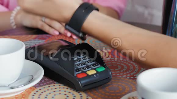 咖啡馆里的年轻人正在使用智能手表和终端机来支付价格视频的预览图