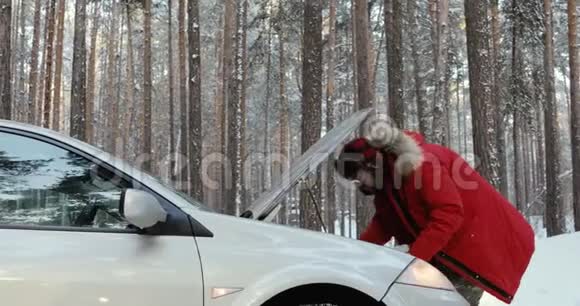 看着汽车发动机的人修理破车的人冬天开车麻烦在一条下雪的乡村道路上视频的预览图
