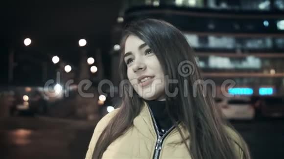 女孩用手修头发看着相机在夜城微笑视频的预览图