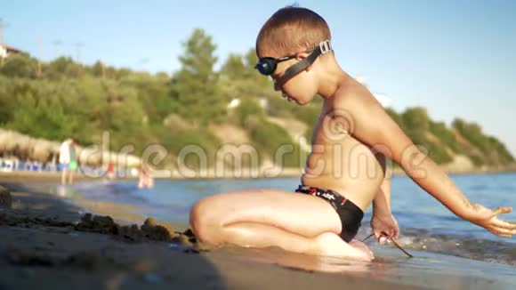 孩子坐在沙滩上享受海浪的冲刷视频的预览图