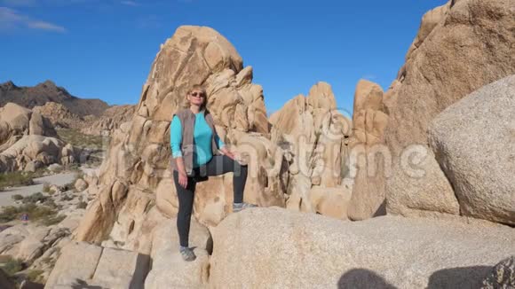 肖像活跃妇女站在岩石上沙色一只腿放在石头上视频的预览图