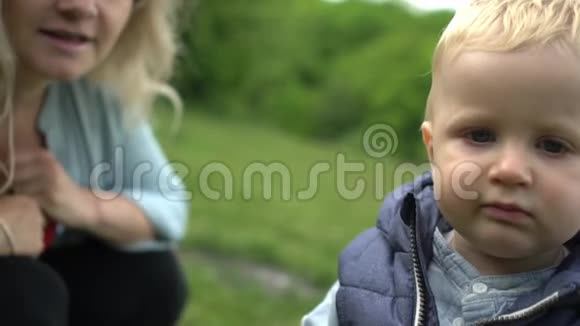 一岁的可爱男孩和他妈妈在公园的第一步慢动作视频的预览图