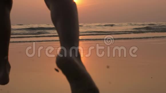 幸福的孩子在美丽的夕阳下奔向大海的剪影视频的预览图