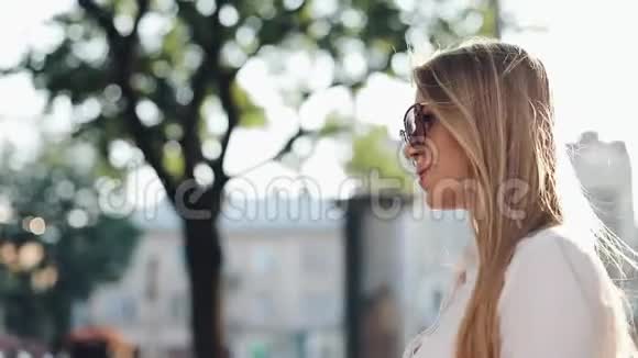 迷人的年轻女子一头华丽的棕色头发戴着时髦的太阳镜迷人的年轻女士正在城里奔波视频的预览图