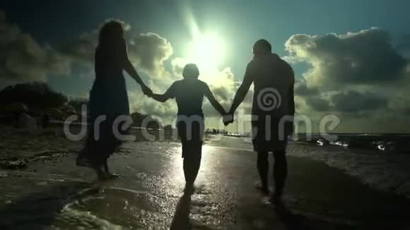 家人在海滩上散步父母和儿子一起沿着海滨散步他们很开心阳光灿烂视频的预览图