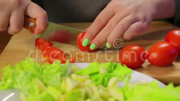 女人用刀在木板上切一个樱桃番茄视频的预览图