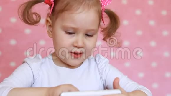 孩子玩手机一个漂亮的小女孩在智能手机上使用游戏应用程序视频的预览图