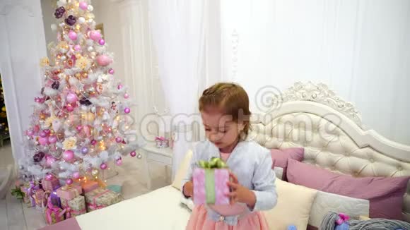 小女孩新年快乐跳床在儿童房粉红背景圣诞树与玩具视频的预览图