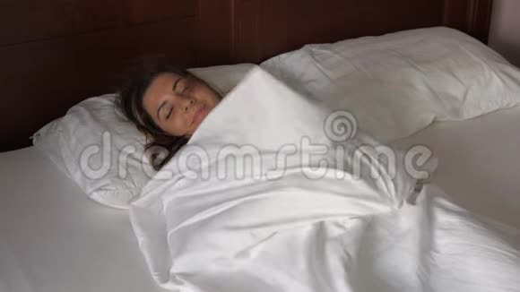 布吕内的女人躺在被罩下的床上拉着毛毯带着欢乐的微笑视频的预览图