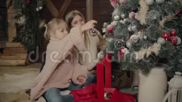 圣诞快乐新年快乐妈妈和女儿在室内装饰圣诞树充满爱的家庭视频的预览图