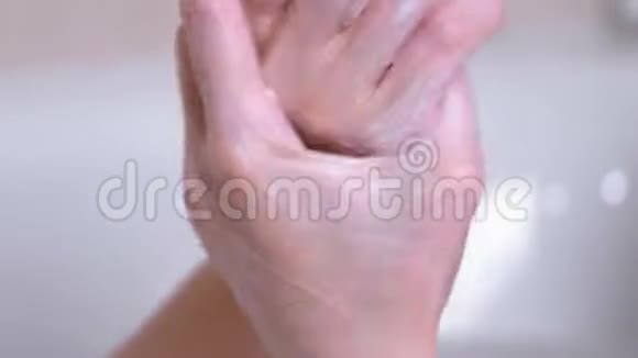 女人剥皮的手把一个擦洗在她的手躺在泡沫浴室双手特写白色背景视频的预览图