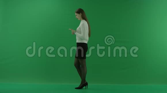女孩站在她的左边转动手中的把手在绿色的屏幕上思考着什么视频的预览图