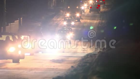 一列汽车在冬天的道路上夜间行驶从前灯上闪闪发光视频的预览图