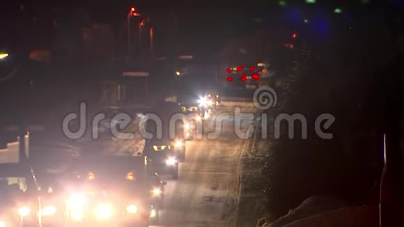 一列汽车在冬天的道路上夜间行驶从前灯上闪闪发光视频的预览图