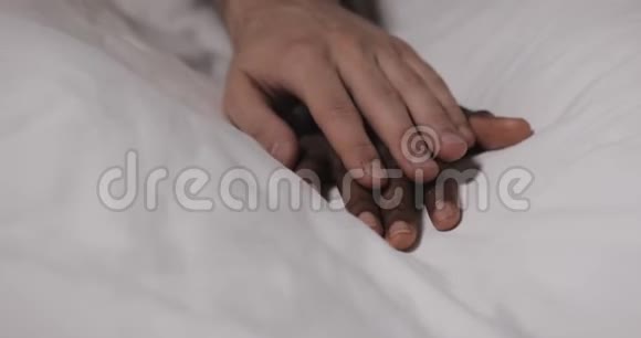 恋爱中的多民族夫妇躺在床上快关门女人的手躺在床上男人的手在抚摸它视频的预览图