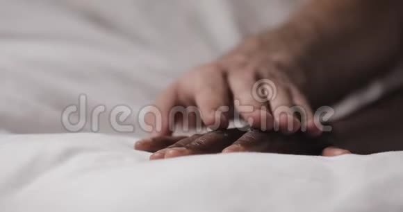 恋爱中的多民族夫妇躺在床上快关门女人的手躺在床上男人的手在抚摸它视频的预览图